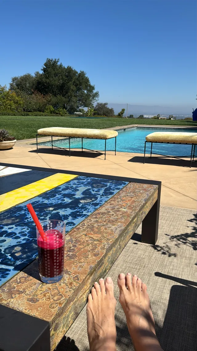 Heidi Klum stretching her bare feet beside an outdoor pool.