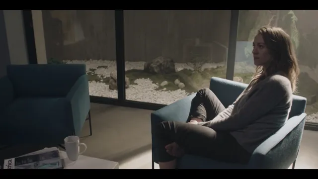 Yvonne Strahovski reclining on a chair beside a window during a screen scene.