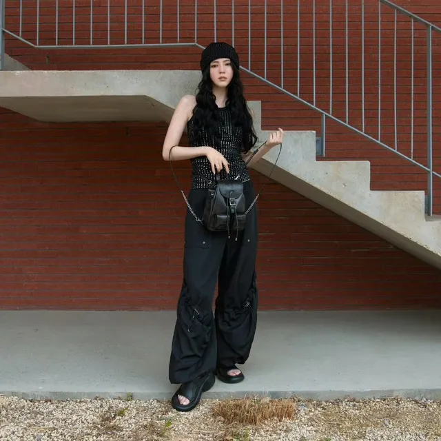 Han So-hee standing outdoors in a black outfit and sandals.