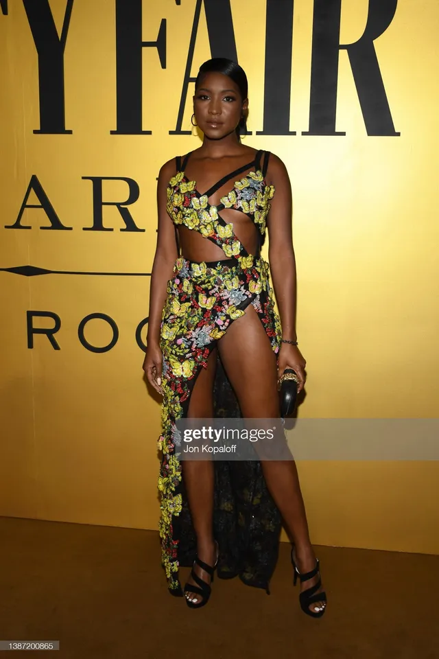 Carlacia Grant posing in a patterned dress and strappy black heels.