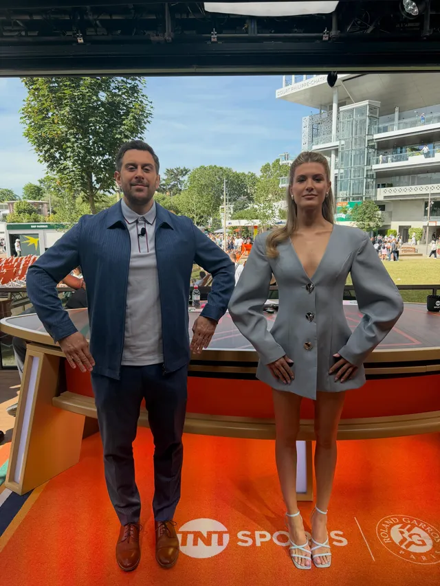 Eugenie Bouchard posing beside a presenter in pale heeled sandals and a grey outfit.
