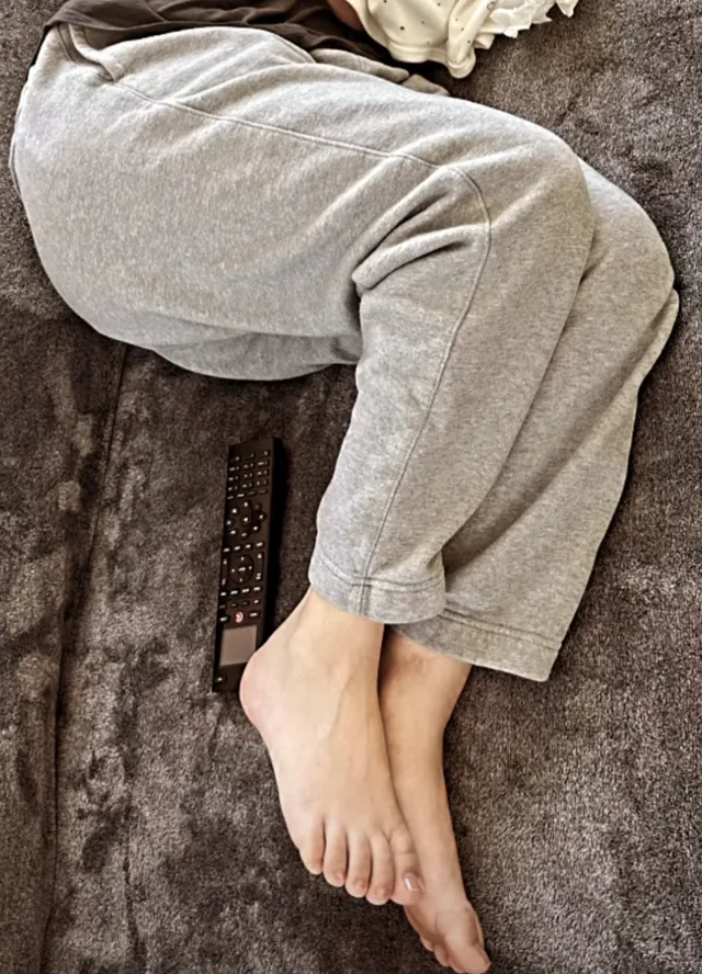Kaley Cuoco curling her bare feet beneath grey trousers.
