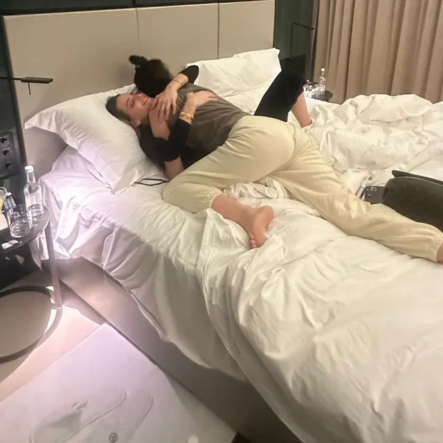 Gal Gadot reclining on a bed with bare feet visible.