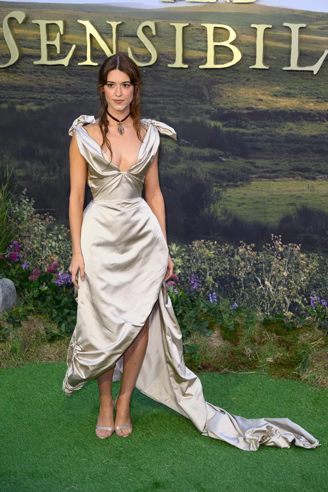 Daisy Edgar-Jones posing before a premiere backdrop in a silver gown.