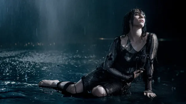 Billie Eilish seated barefoot in shallow water in a screen scene.
