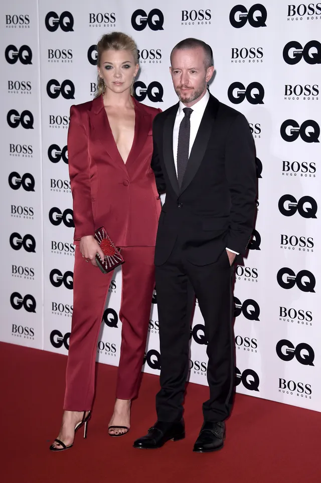 Natalie Dormer posing with a guest in a red trouser suit.