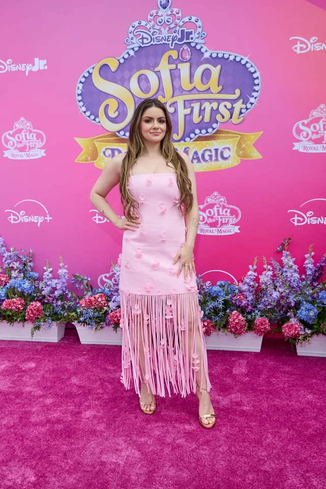 Ariel Winter posing at an event in a pink fringed dress.