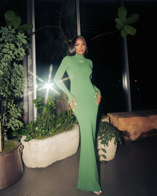 Ryan Destiny posing outdoors at night in a long green gown.
