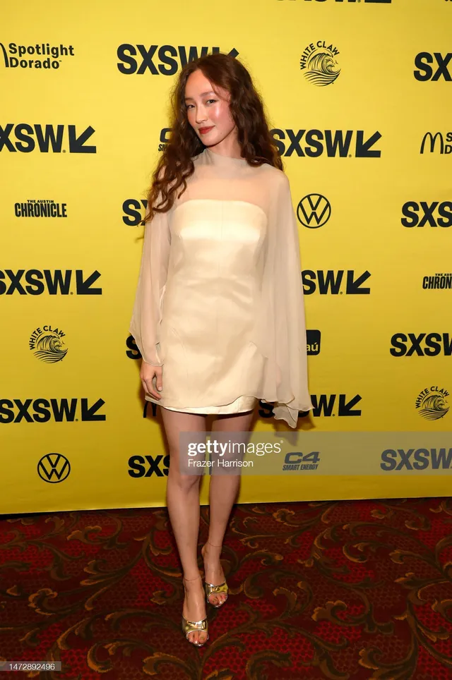Havana Rose Liu posing in a pale dress and gold heels.