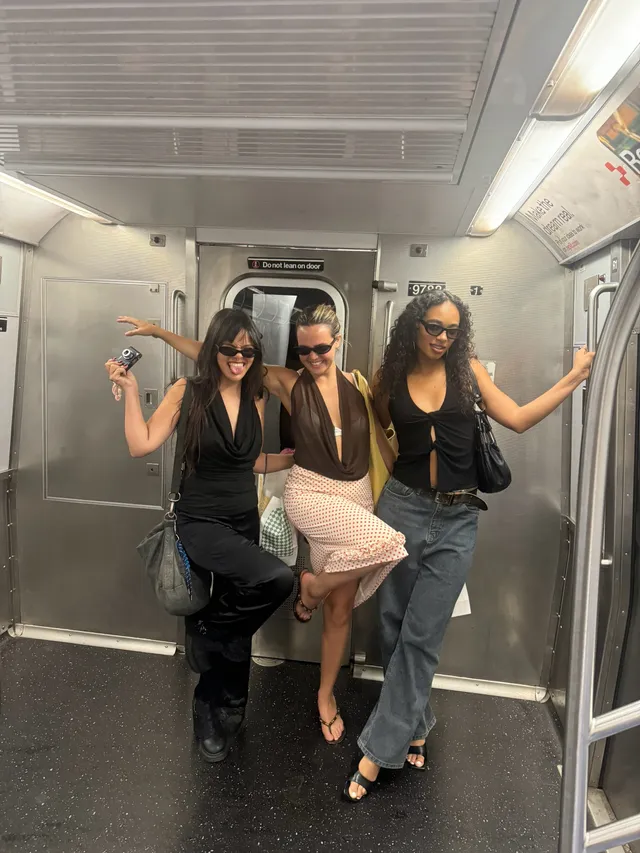 Bailee Madison posing with friends in heeled sandals on a train.