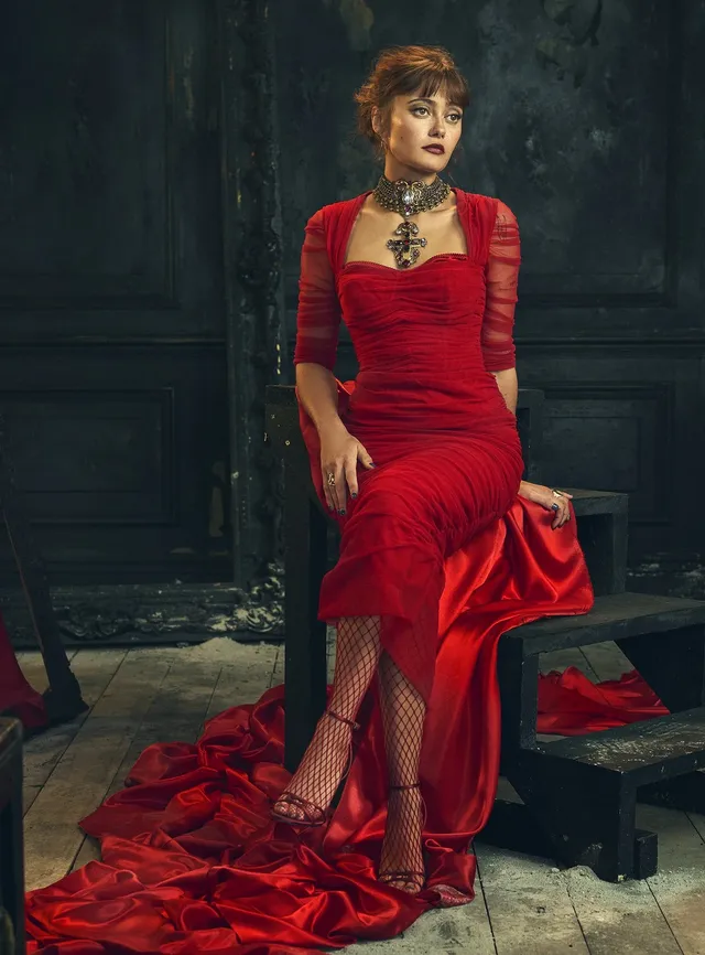 Ella Purnell posing in a red gown and matching sandals.