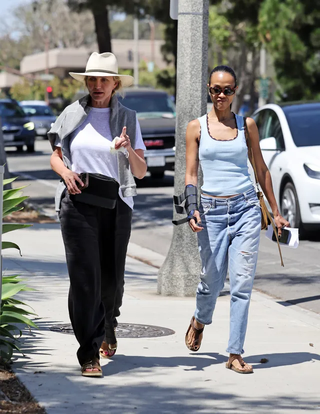 Zoe Saldaña walking outdoors in jeans and a pale blue top.