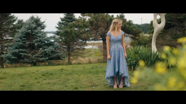 Emily Alyn Lind standing barefoot outdoors in a flowing blue dress.