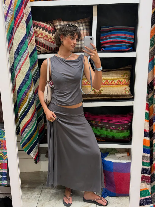 Taylor Hill wearing flat sandals with a grey dress outside a clothing shop.