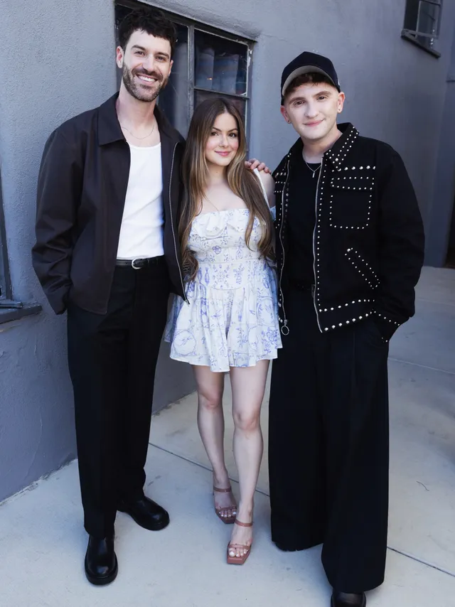 Ariel Winter posing with companions in a pale dress.