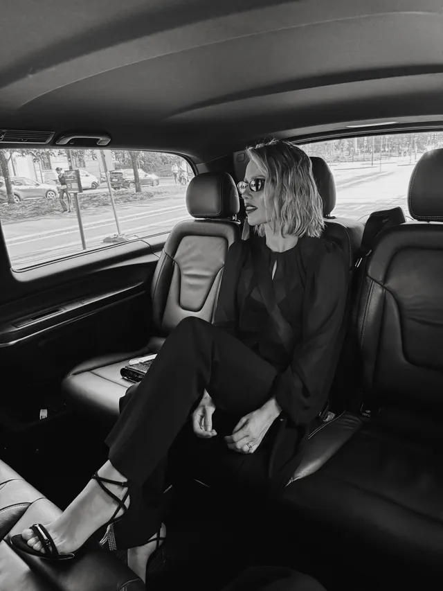 Claire Holt sitting in a vehicle for a black-and-white portrait.