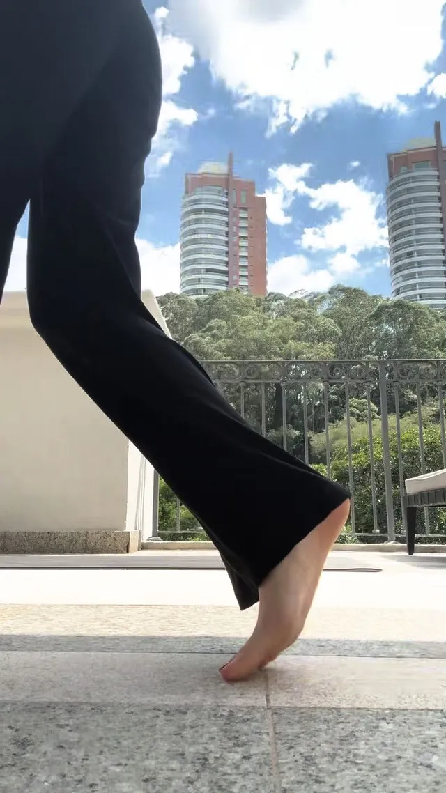 Olivia Rodrigo lifting one heel while standing outdoors.