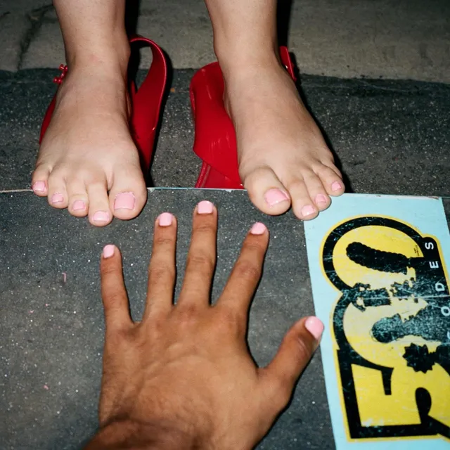 Cailee Spaeny showing her bare feet beside a pair of red shoes.