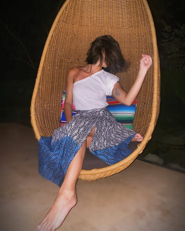 María Gabriela de Faría posing barefoot in a hanging chair.