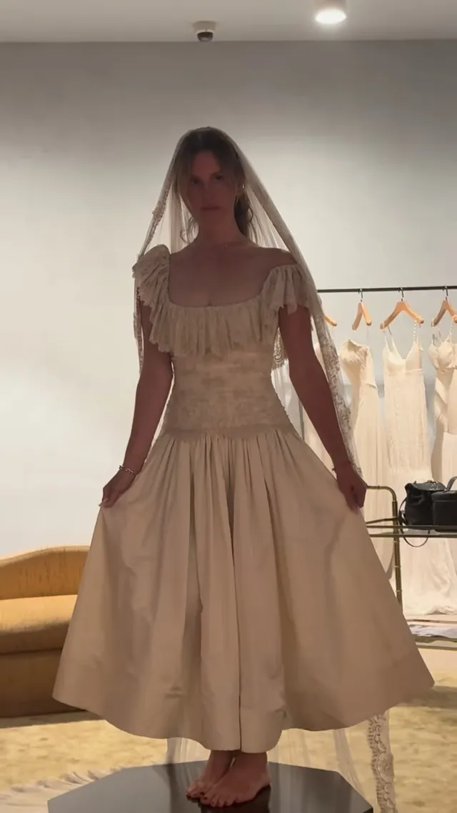 Lana Del Rey standing barefoot in a pale dress during a fitting.