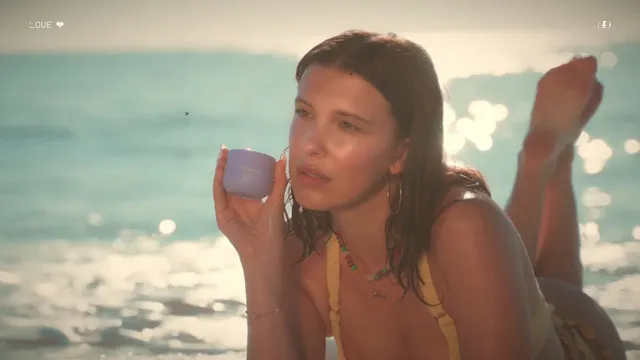 Millie Bobby Brown: reclining barefoot on a beach with her feet raised.