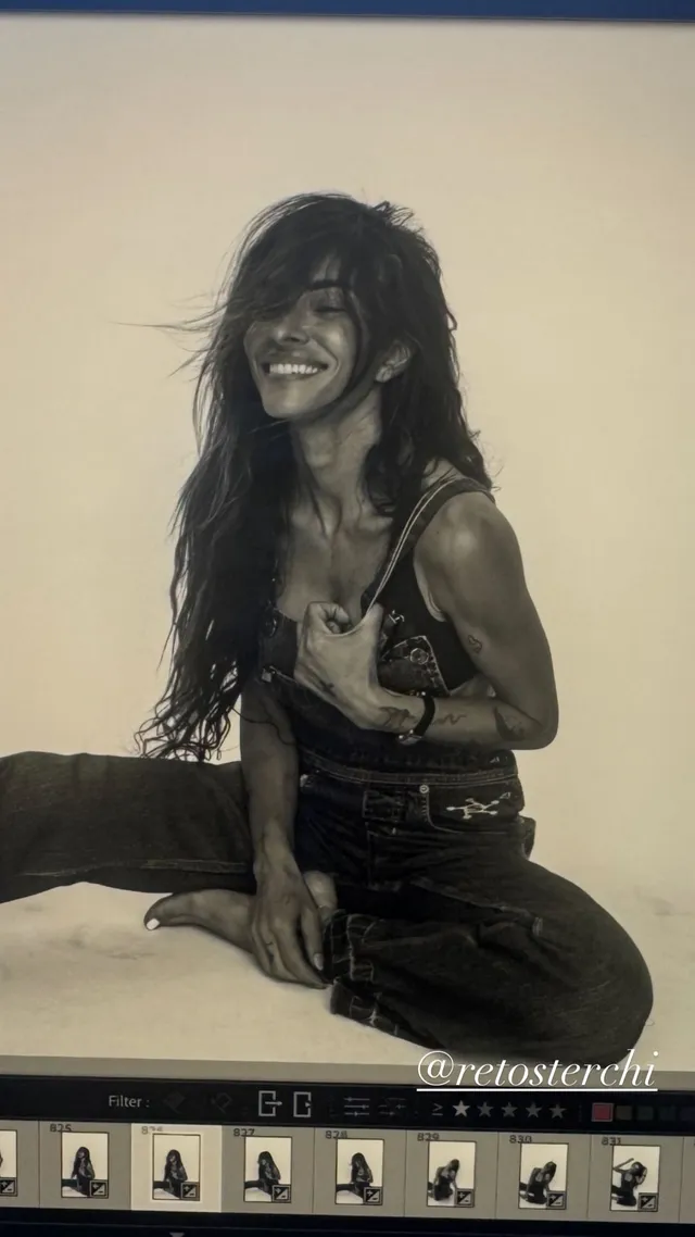 Sarah Shahi sitting for a black-and-white portrait in a dark outfit.
