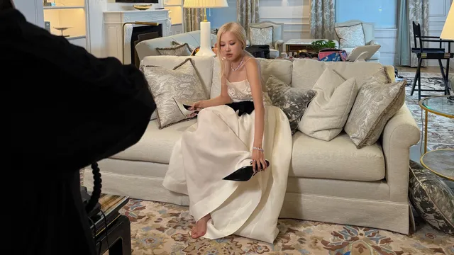 Rosé sitting on a cream sofa in a pale skirt and black pumps.