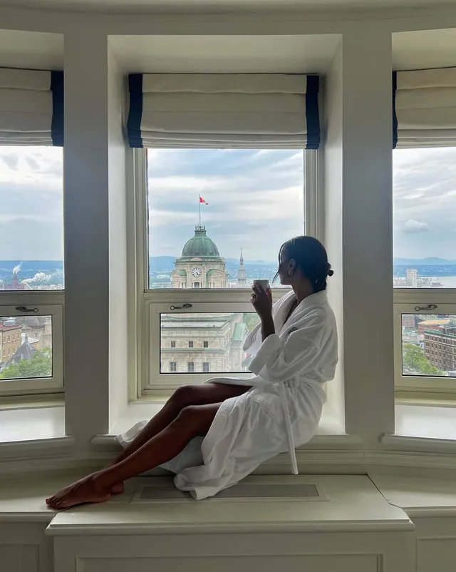 Greta Onieogou sitting barefoot in a bathrobe on a window ledge.