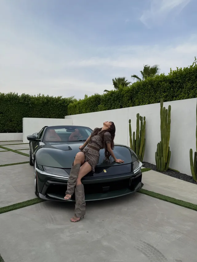 Lisa (Lalisa Manobal) leaning against a vehicle in tall open-toe heels and a patterned dress.