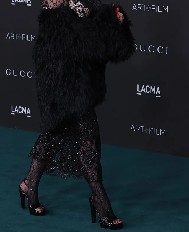 Billie Eilish a close view of dark heels beneath a lace dress.