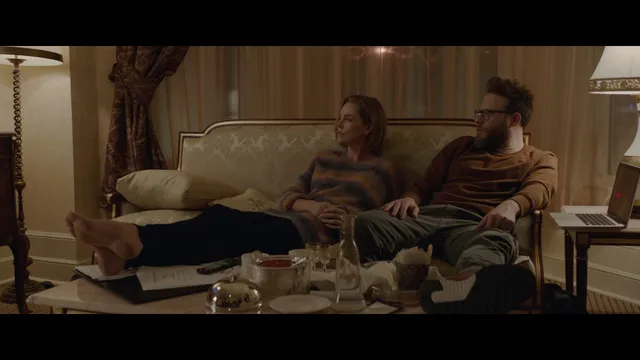 Charlize Theron a reclining sofa screen scene beside another character.