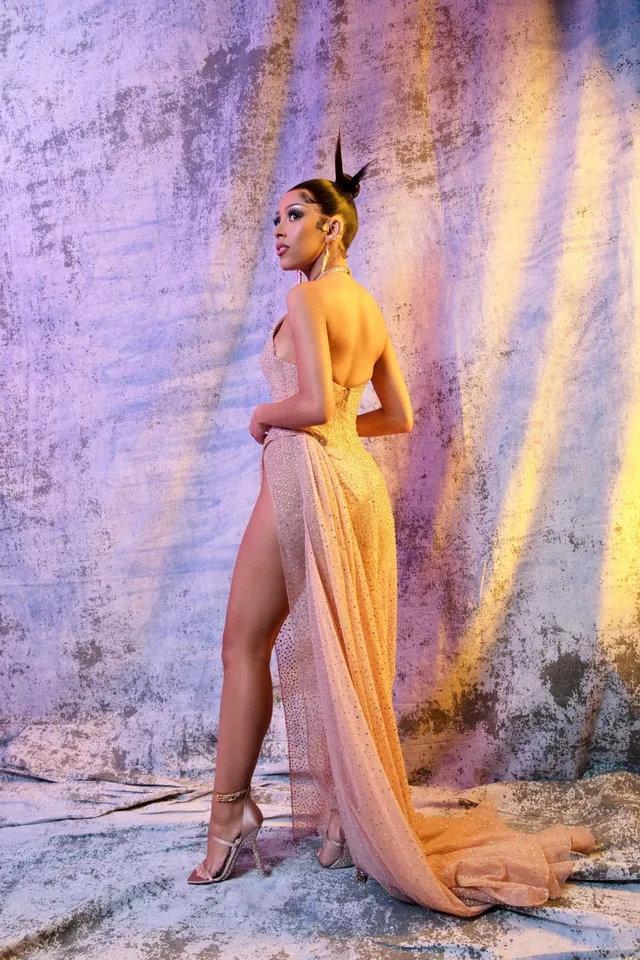 Doja Cat posing in a long pale dress and strappy heels.