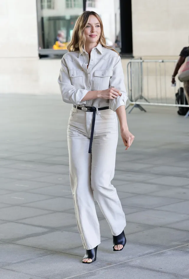 Jodie Comer walking outside in a white outfit.