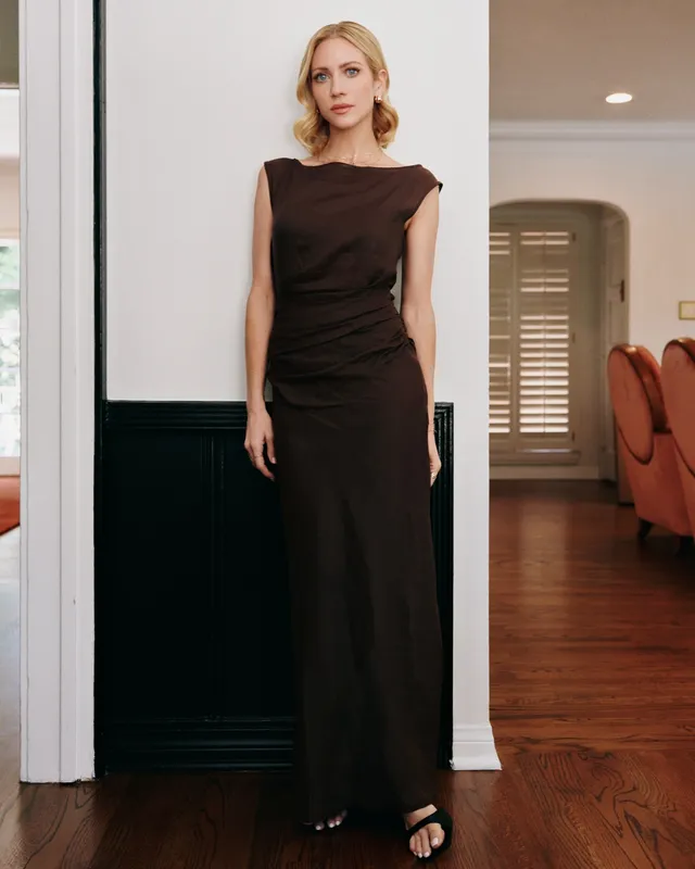 Brittany Snow posing indoors in a long dark dress.