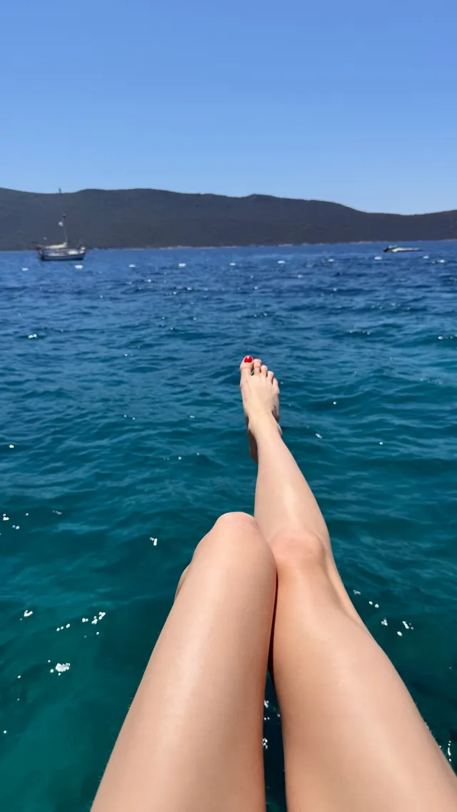 Anya Taylor-Joy extending a bare leg above blue seawater.
