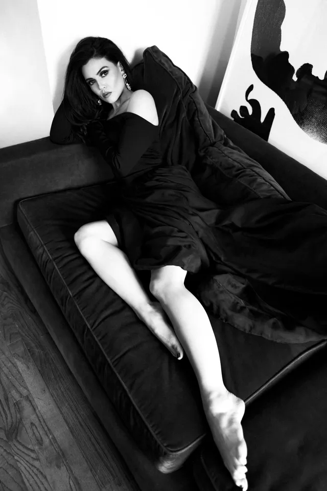 Danielle Campbell reclining on a sofa for a black-and-white portrait.