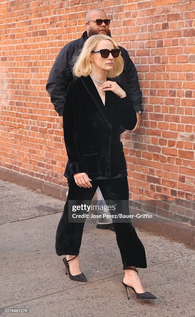 Jessica Chastain walking outdoors in a black velvet suit.