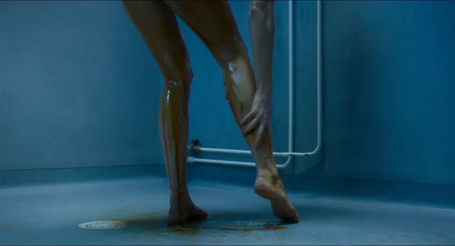Eva Green a dimly lit screen detail of bare feet on a blue floor.