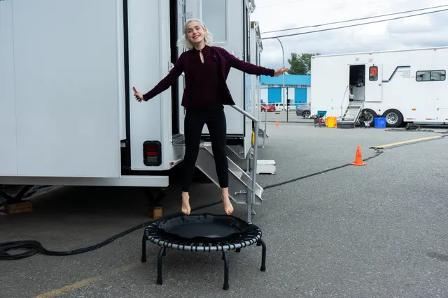 Kiernan Shipka standing barefoot on a small trampoline outside a trailer.