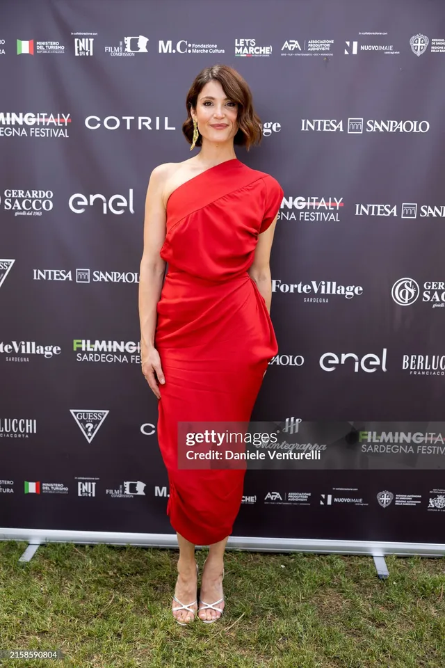 Gemma Arterton posing outdoors in a red dress.