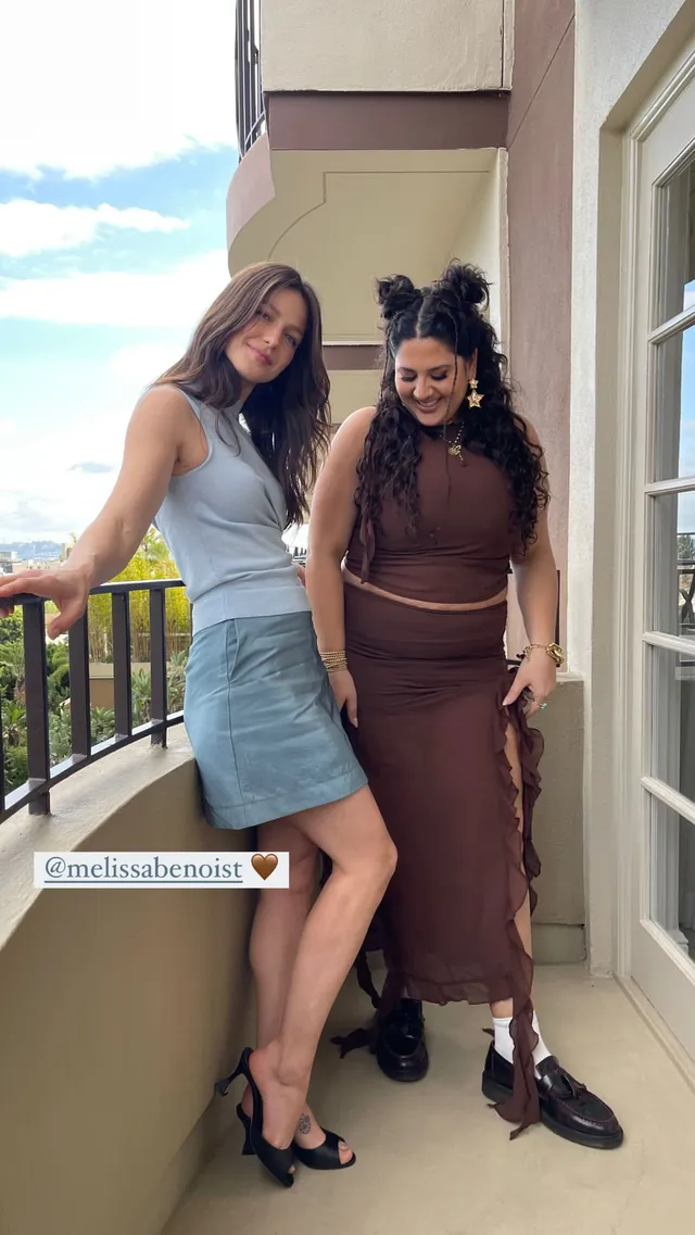 Melissa Benoist posing beside another woman in a denim skirt and heels.