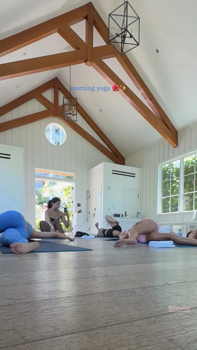 Victoria Justice stretching barefoot on a wooden floor with other people.