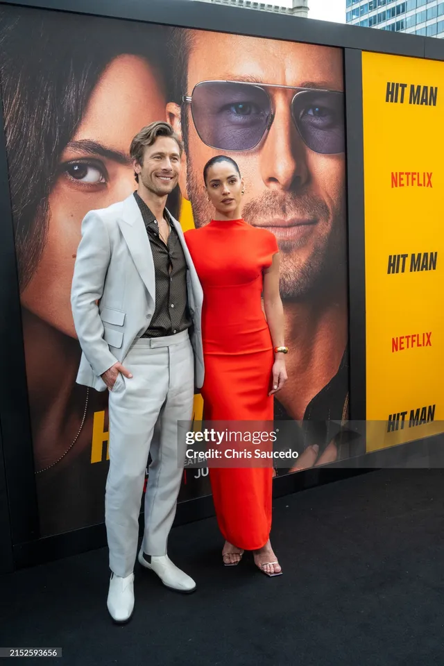 Adria Arjona wearing a red gown and pale heels at a premiere.