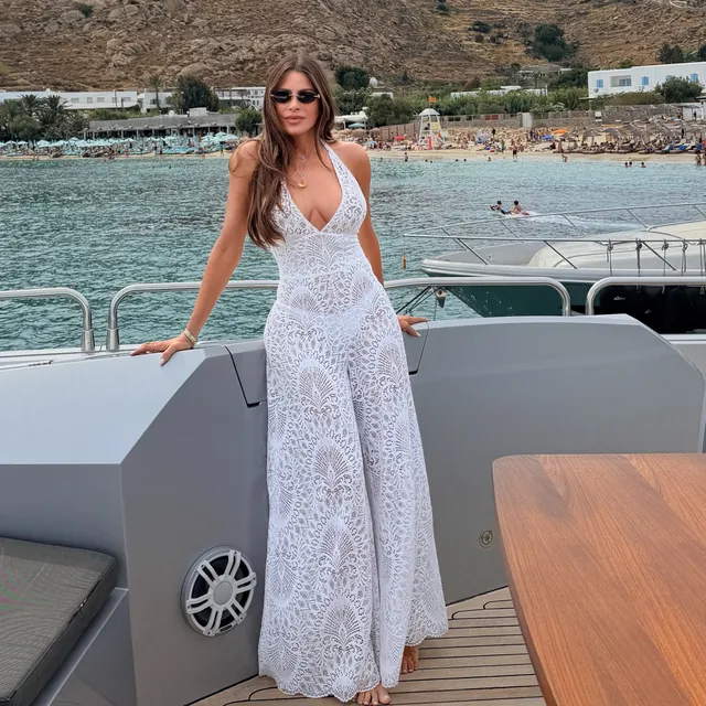 Sofía Vergara standing on a boat in a long white lace dress.