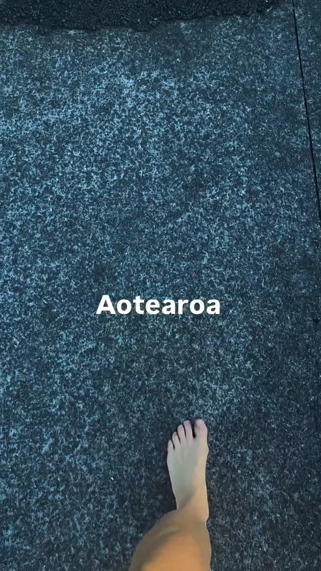 Tove Lo walking barefoot across dark carpet.