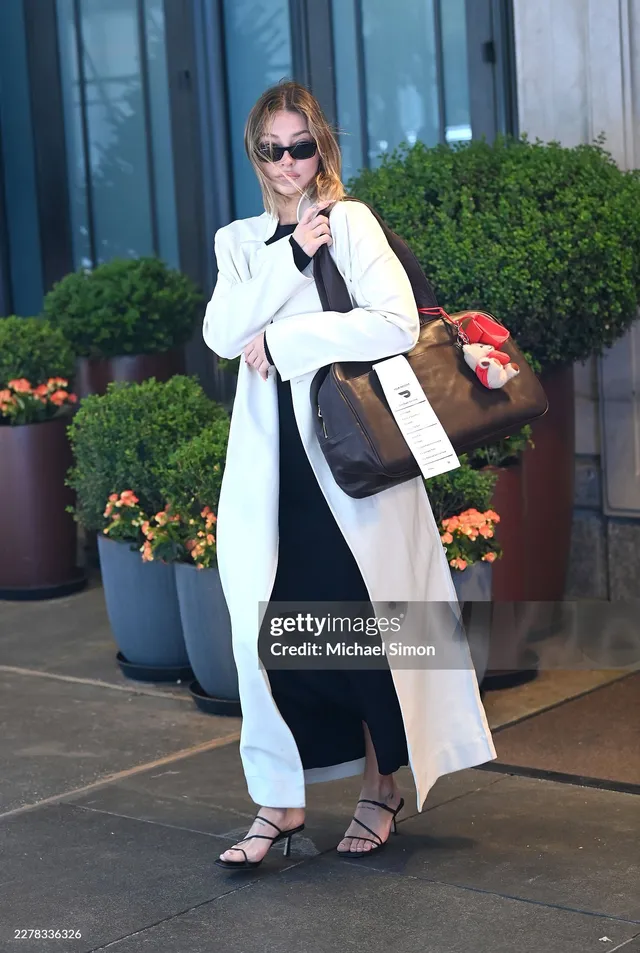 Madelyn Cline wearing a pale coat and black heeled sandals outdoors.