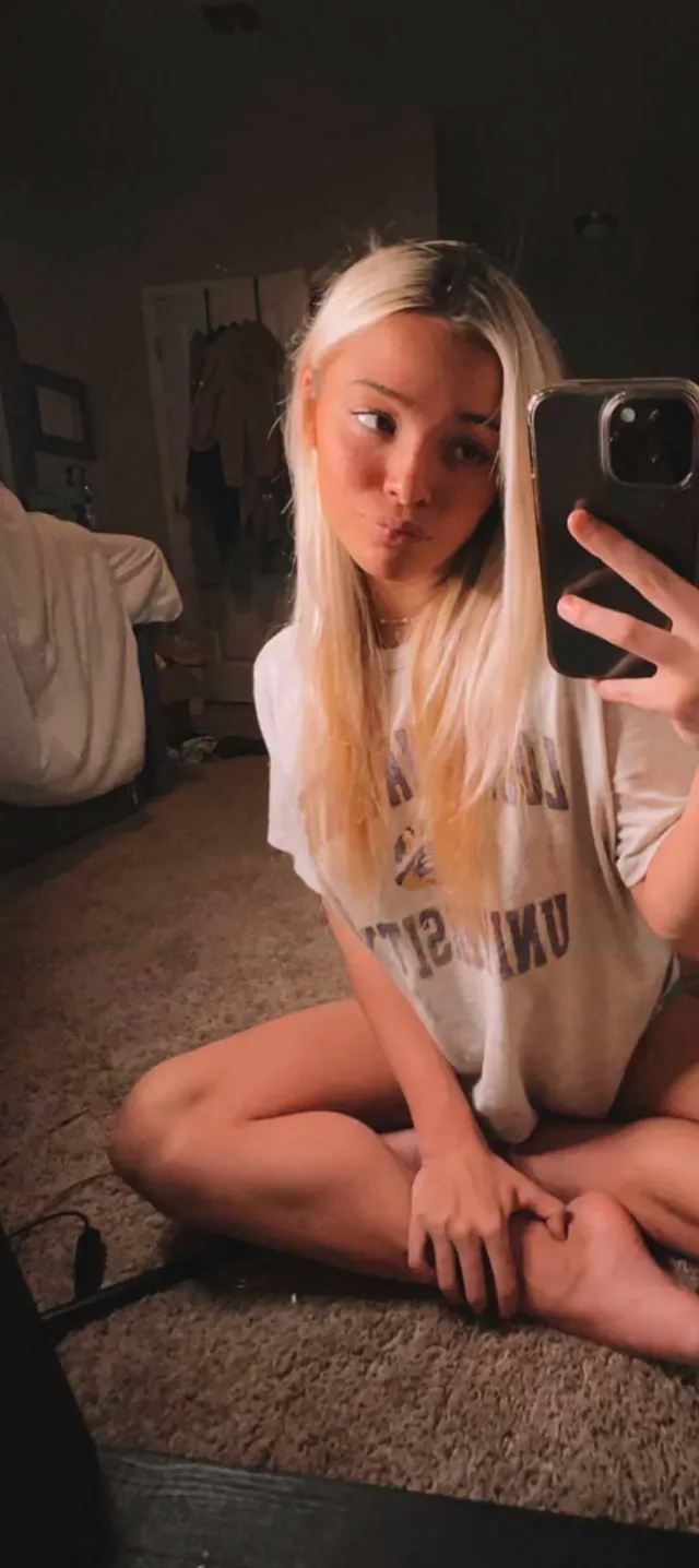 Olivia Dunne sitting cross legged barefoot for an indoor mirror photo.