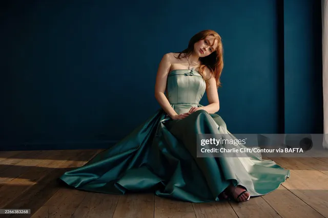 Sadie Sink sitting in a green gown and heels for a portrait.