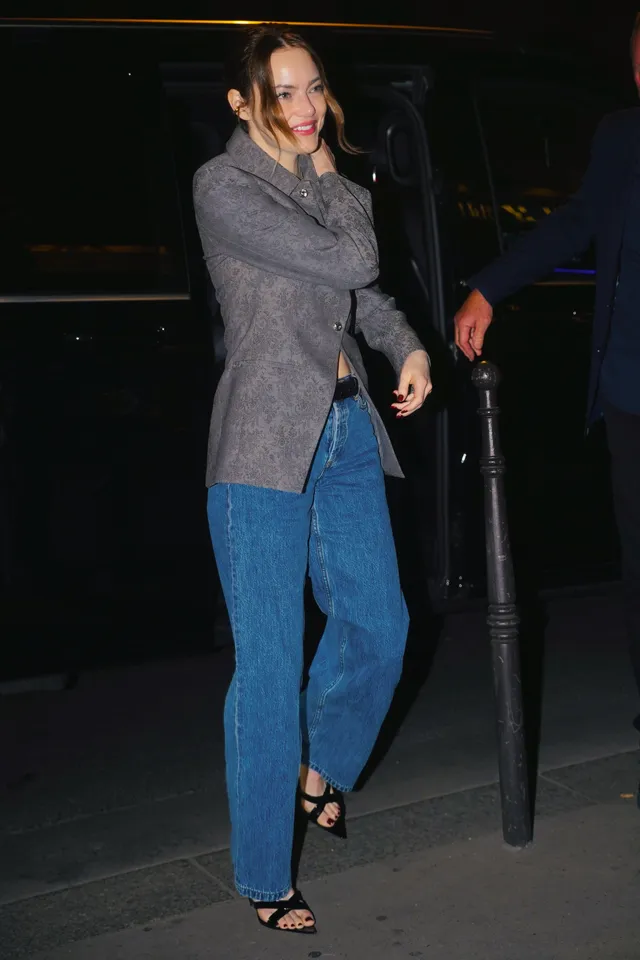 Emma Stone wearing a gray blazer, blue jeans and black open-toe heels.