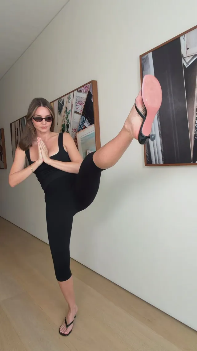Miranda Kerr a raised sandal while posing in black.